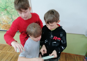 Trzech chłopców czytających kartkę