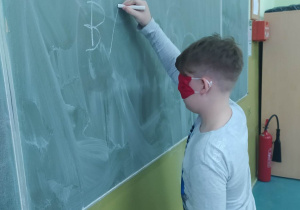 Dziecko z zasłoniętymi oczami pisze na tablicy