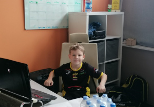 Chłopiec siedzi za biurkiem