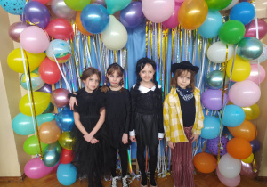 Dzieci w strojach karnawałowych, na ściance balonowej, pozują do zdjęcia