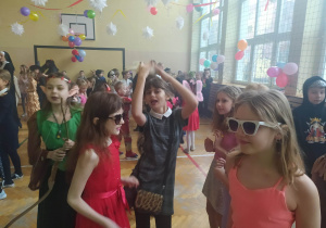 Dzieci w strojach karnawałowych tańczą na sali balowej