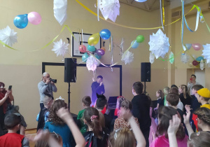 Dzieci w strojach karnawałowych tańczą na sali balowej