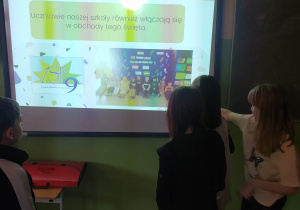 Dzieci stoją przy tablicy z rysunkiem kolorowych skarpetkek