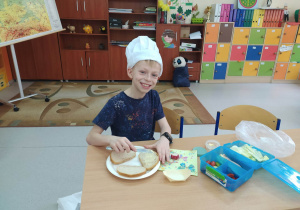 Chłopiec w czapce kucharza robi kanapki wiosenne
