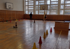 Dziecko z nauczycielem pokonuje przeszkody na sali gimnastycznej