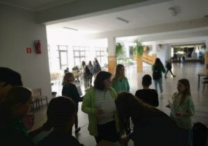 Duża grupa dzieci ubrana na zielono wypełnia Quiz na korytarzu szkolnym