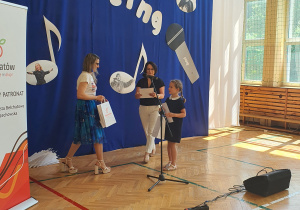 Kobiety i dziewczynka z mikrofonem na tle napisu Let's Sing