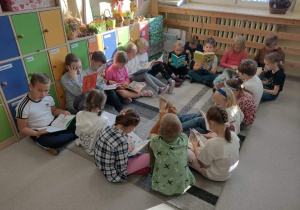 Dzieci siedzące na dywanie czytają książki