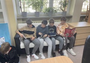 Chłopcy siedzący na kanapie czytają książki