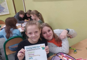 Dziewczynki pokazują napis cechy dobrego wolontariusza