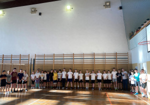 Uczniowie na sali gimnastycznej, stoją dookoła sali