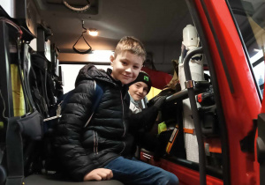 Chłopiec siedzi za kierownicą wozu strażackiego