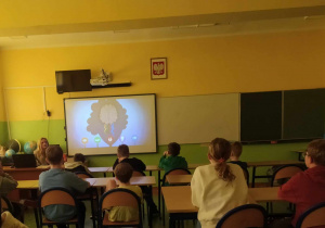 Dzieci w ławkach oglądają film na ekranie