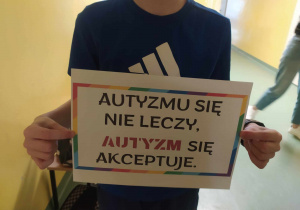 Dziecko trzyma plakat z napisem, autyzmu się nie leczy, autyzm się akceptuje.