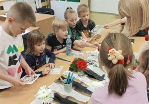 Dzieci przy stolikach malują torby