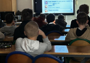 Uczniowie siedzą w ławkach i oglądają film edukacyjny