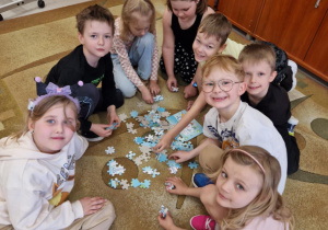 Uśmiechnięte dzieci układają puzzle na dywanie