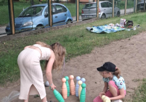 Dzieci na dworze ustawiają kolorowe kręgle
