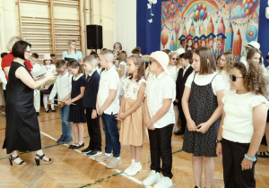 Uśmiechnięte dzieci stoją w rzędzie i odbierają nagrody