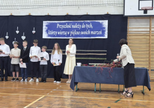 Panie i uśmiechnięte dzieci z nagrodami, stoją w rzędzie