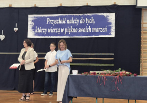 Panie i uczniowie na tle granatowej dekoracji