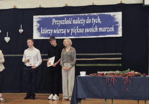 Panie i uczniowie na tle granatowej dekoracji