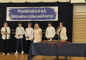 Panie i uczniowie na tle granatowej dekoracji