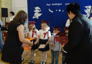 Kobieta wręcza dzieciom dyplomy