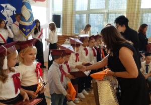 Kobieta wręcza dzieciom dyplomy