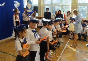 Kobieta wręcza dzieciom dyplomy