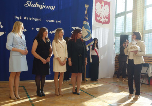 Uśmiechnięte kobiety stoją obok siebie na przeciw pani trzymającej prezent