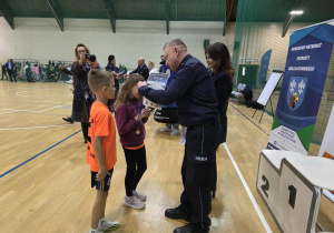 Dzieci w strojach sportowych przyjmują medale