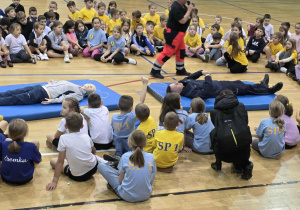 Radosne dzieci w strojach sportowych siedzą dookoła materacy