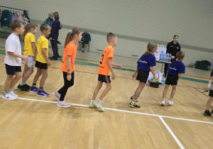 Dzieci w strojach sportowych stoją w rzędzie do biegu