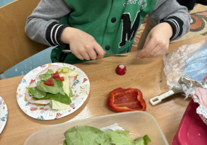 Uśmiechnięty chłopiec przygotowuje kolorową kanapkę