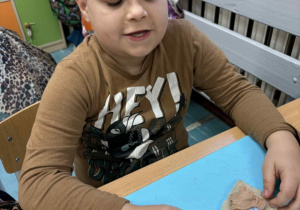 Uśmiechnięty chłopiec siedzi przy stoliku a przed nim kolorowa kanapka