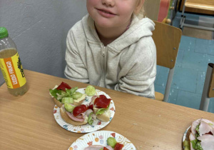 Uśmiechnięta dziewczynka z kolorową kanapką na talerzu