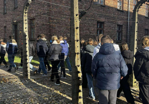 Grupa młodzieży idzie przy drutach kolczastych