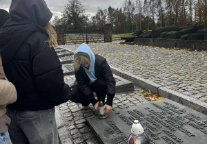 Dziewczyna stawia znicz na pomniku