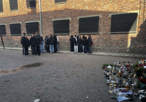 Grupa młodzieży stoi pod murem