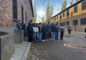 Grupa młodzieży stoi pod murem