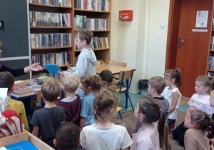 Radosne dzieci siedzą w bibliotece z kobietą