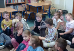 Radosne dzieci siedzą na podłodze wśród książek