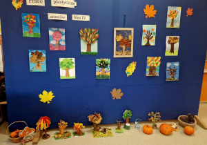 Wystawa obrazów z kolorowymi drzewami na niebieskim tle.