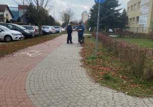 Uczeń wręcza ulotkę mężczyźnie z psem