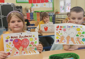 Dzieci z namalowanymi sercami na białych kartkach