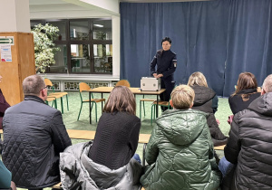 Kobieta w stroju policyjnym stoi przed grupą ludzi