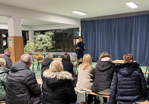 Kobieta w stroju policyjnym stoi przed grupą ludzi