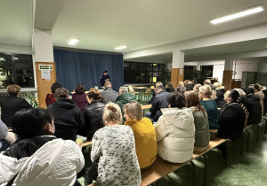 Kobieta w stroju policyjnym stoi przed grupą ludzi