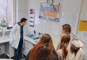 Mężczyzna w białym fartuchu pokazuje mikroskop